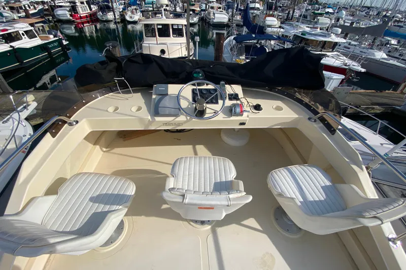 Slide: The Image of Flybridge of Camano 30 boat with three white seats, overlooking marina. - 34