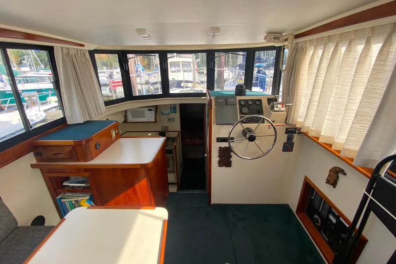 Slide: The Image of Interior of Camano 30 boat with helm, seating, and windows overlooking marina. - 4