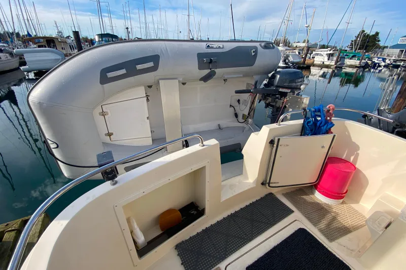 Slide: The Image of Camano 30 boat deck with dinghy and outboard motor in marina setting. - 42