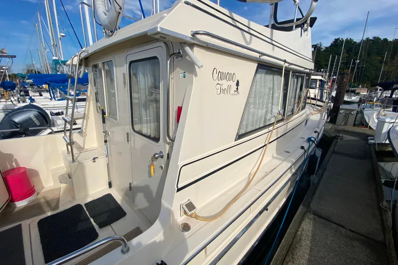 Slide: The Image of Camano 30 boat docked at marina, featuring side view and entry door. - 44