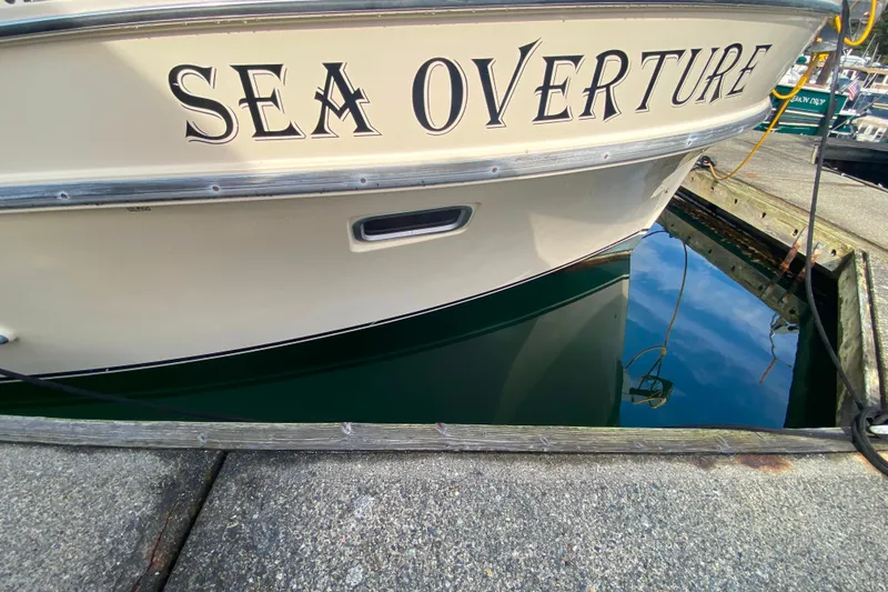 Slide: The Image of Camano 30 boat named "Sea Overture" docked at a marina, reflecting in water. - 47