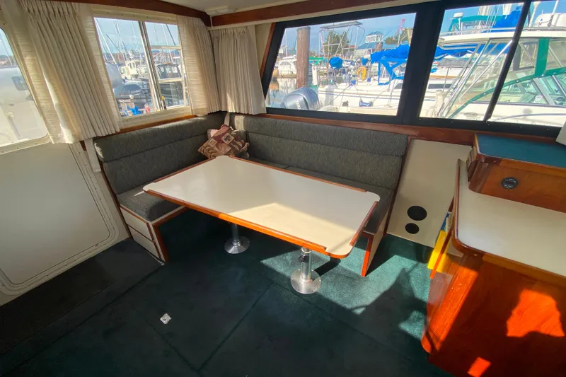 Slide: The Image of Interior of Camano 30 boat with dining area, table, and windows overlooking marina. - 5