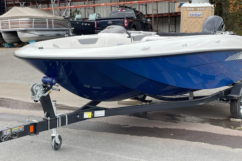 Slide: The Image of 2026 Bayliner Element E18 boat on trailer, blue hull, parked outdoors. - 2