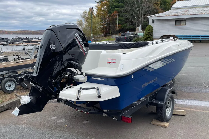 Slide: The Image of 2026 Bayliner Element E18 boat with Mercury engine on trailer, parked near a lake. - 4