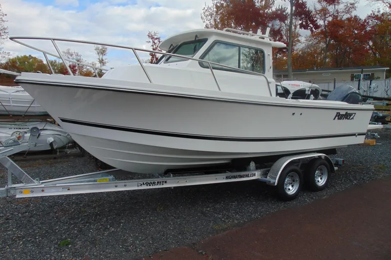 The Image of 2026 Parker 227 Explorer boat on trailer, parked outdoors with autumn trees in background. - 1