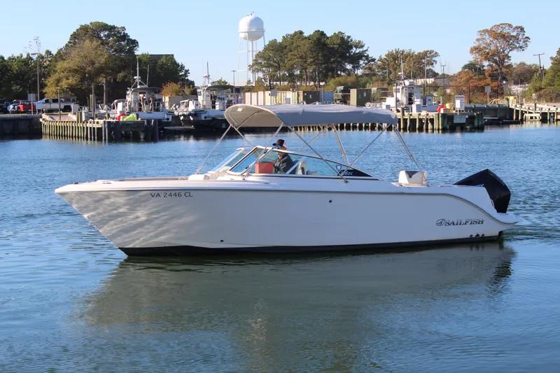 Slide: The Image of 2024 Sailfish 226DC boat cruising on calm water near a marina. - 1