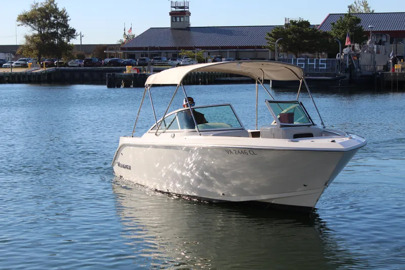 Slide: The Image of 2024 Sailfish 226DC boat cruising on calm water near a marina. - 8