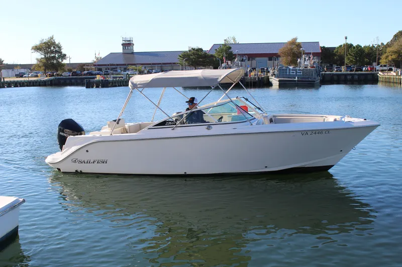 Slide: The Image of 2024 Sailfish 226DC boat on calm water near a marina. - 9