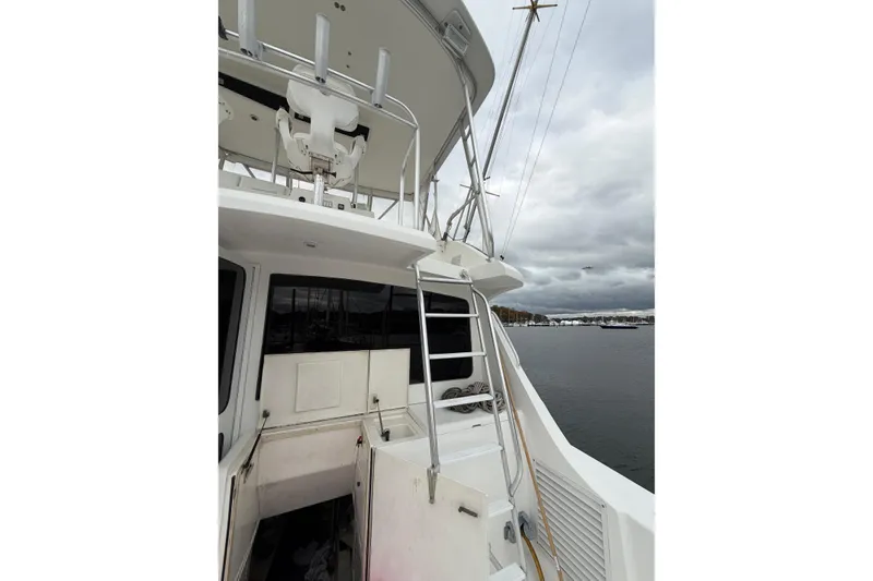 Slide: The Image of 2001 Egg Harbor 42 SportYacht docked, showcasing upper deck and ladder under cloudy skies. - 4