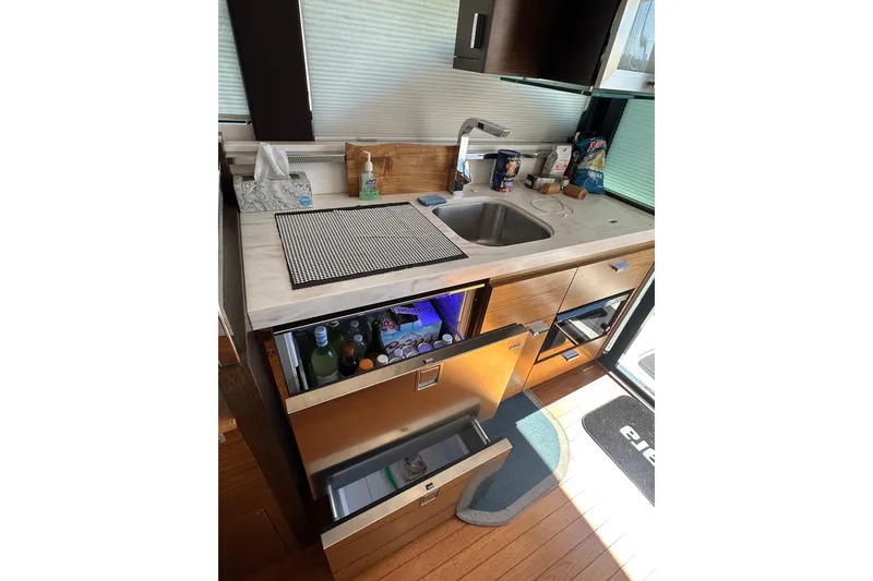 Slide: The Image of 2018 Tiara Yachts C39 Coupe kitchen with sink, open fridge, and wooden cabinetry. - 16