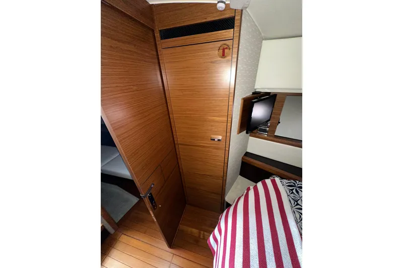 Slide: The Image of 2018 Tiara Yachts C39 Coupe interior with wood paneling and striped bedding. - 29