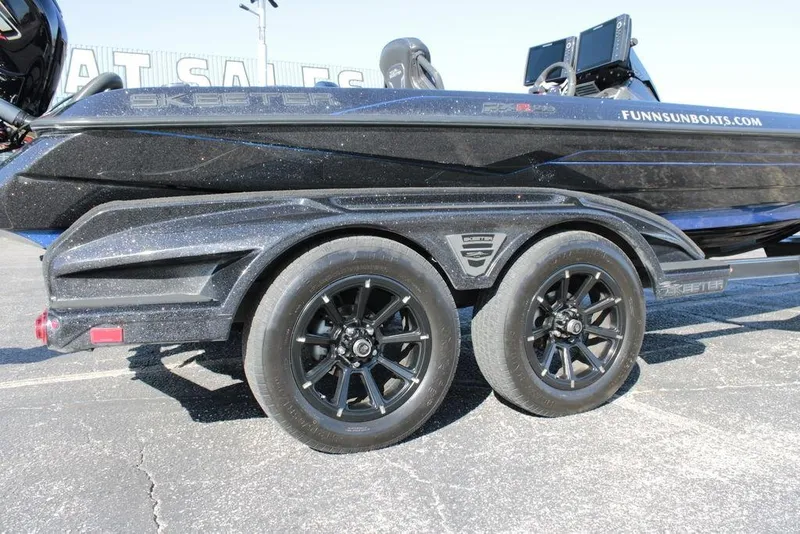 Slide: The Image of 2025 Skeeter FXR21 Limited boat trailer with black wheels, parked outdoors. - 20