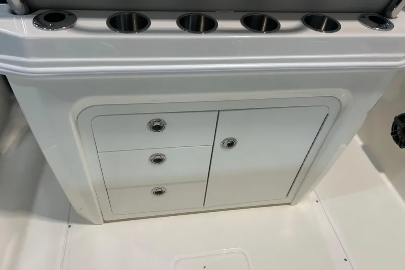 Slide: The Image of 2025 Boston Whaler 220 Dauntless storage compartment with rod holders and sleek design. - 13