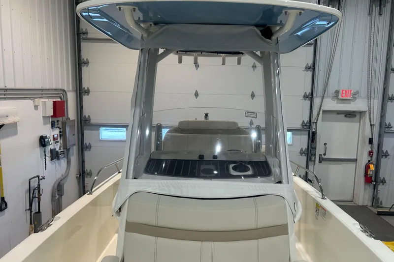Slide: The Image of 2025 Boston Whaler 220 Dauntless boat in indoor storage, showcasing helm and seating area. - 25
