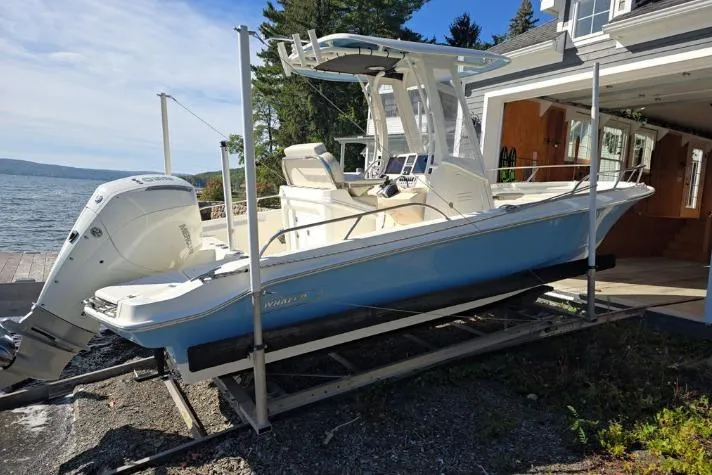 Slide: The Image of 2025 Boston Whaler 220 Dauntless boat on a lift by a lakeside house. - 30