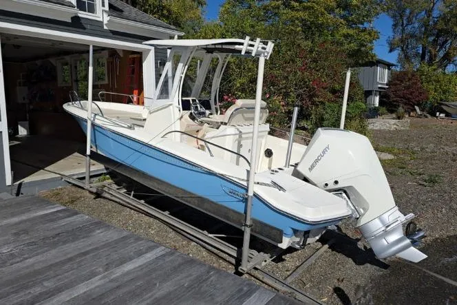 Slide: The Image of 2025 Boston Whaler 220 Dauntless boat with Mercury engine on a trailer, parked outdoors. - 32