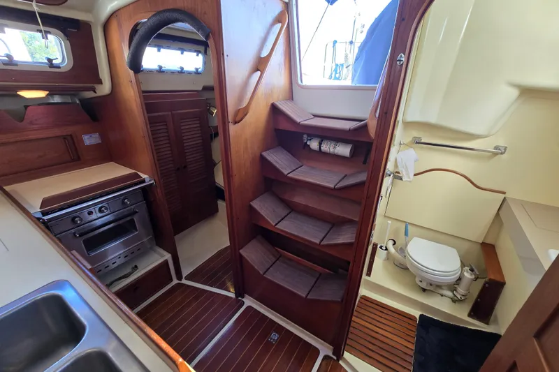 Slide: The Image of 1988 Pearson 362 Centerboard interior with kitchen, wooden stairs, and compact bathroom. - 15