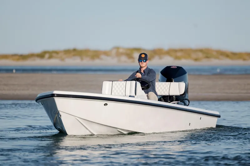 Slide: The Image of Man driving a 2026 Vtech 18 boat on calm water near a sandy shore. - 10