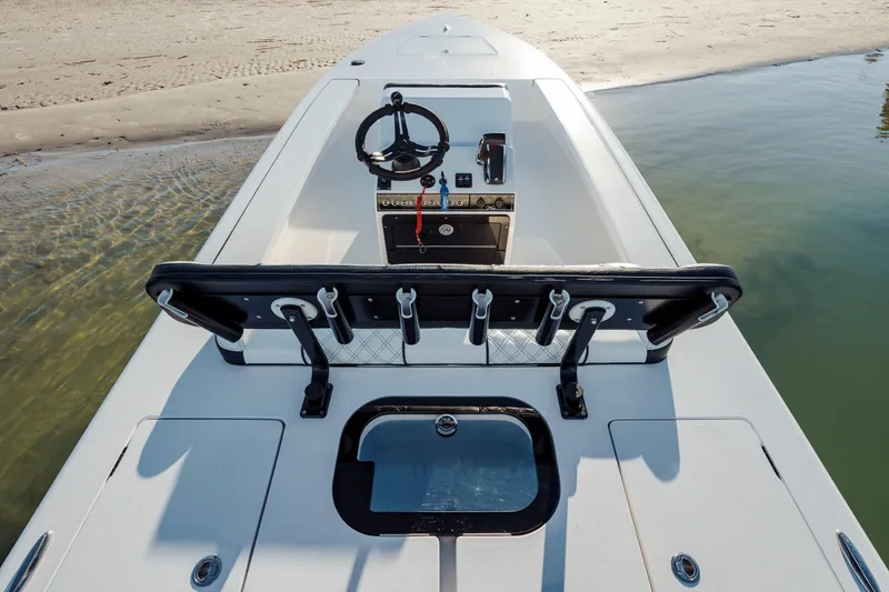 Slide: The Image of 2026 Vtech 18 boat interior with steering wheel, rod holders, and seating near sandy shore. - 13