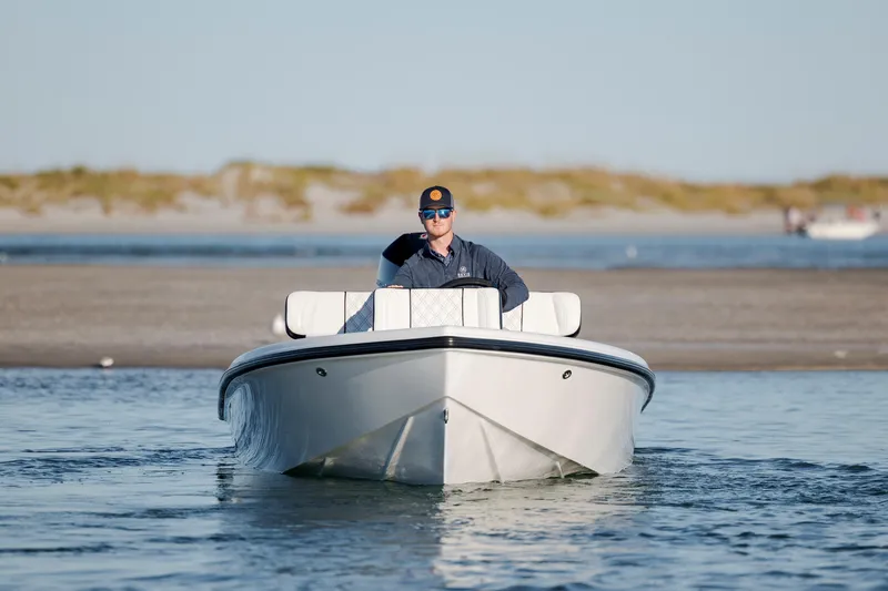 Slide: The Image of Man driving a 2026 Vtech 18 boat on calm water near a sandy shore. - 9