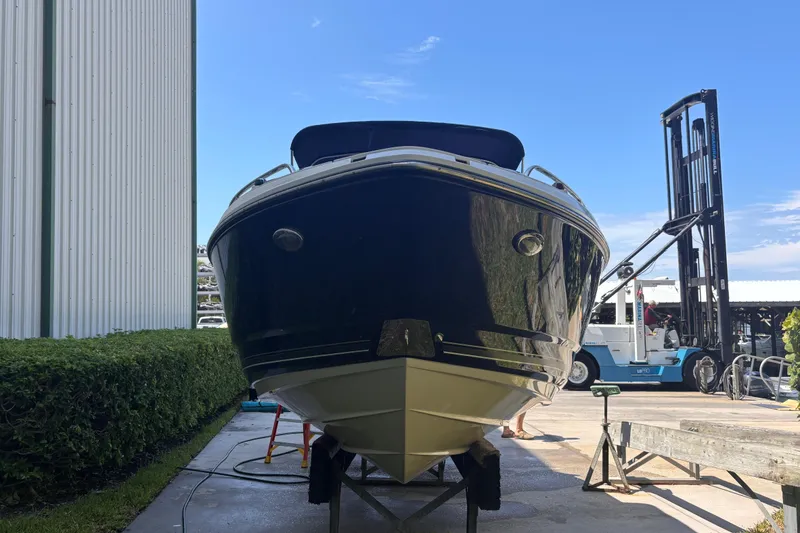 Slide: The Image of 2010 Monterey 254FS boat on trailer, parked outdoors near a building and forklift. - 3