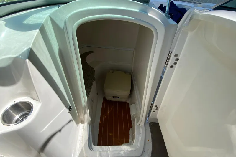 Slide: The Image of 2010 Monterey 254FS boat interior with compact marine toilet and wooden flooring. - 32