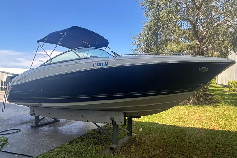 Slide: The Image of 2010 Monterey 254FS boat on stand, blue hull, canopy, sunny day, outdoor setting. - 6