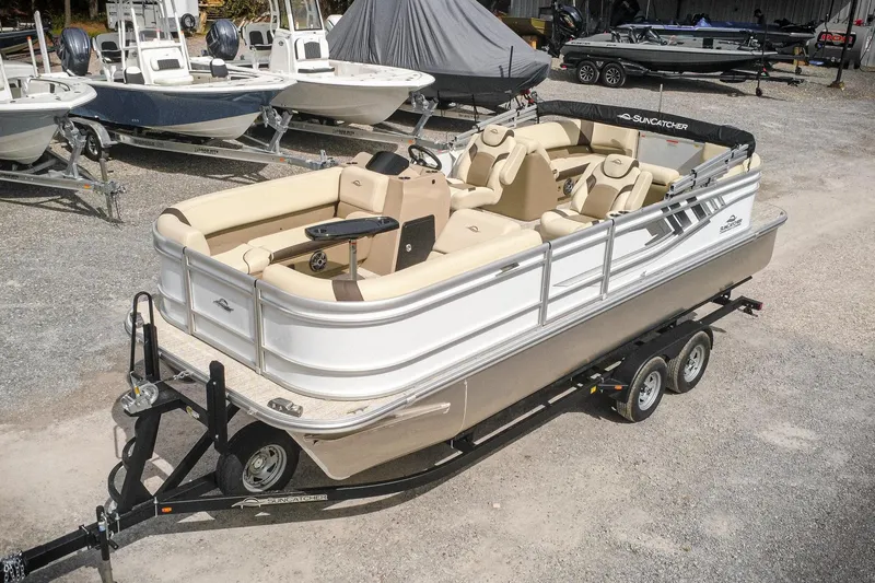 The Image of 2026 SunCatcher Select 22RC pontoon boat on trailer, parked among other boats. - 0