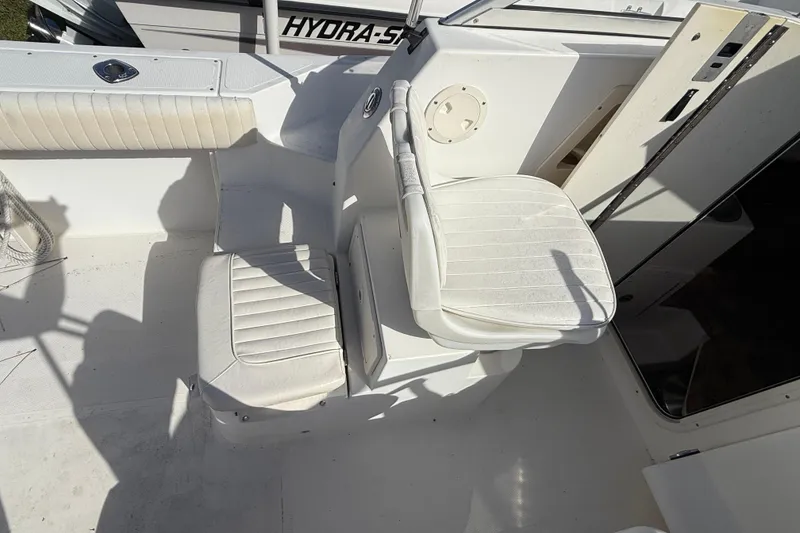 Slide: The Image of 2005 Mako 215 Walk Around boat interior with white seating and clean deck. - 12