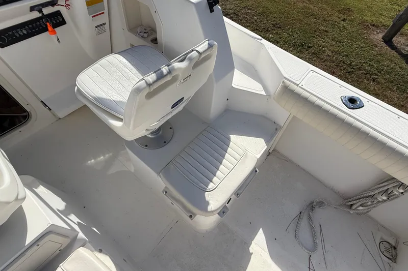 Slide: The Image of 2005 Mako 215 Walk Around boat interior with white seating and control panel. - 13