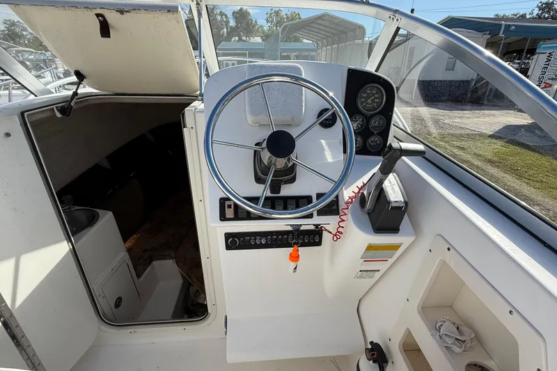 Slide: The Image of 2005 Mako 215 Walk Around boat cockpit with steering wheel and control panel. - 14