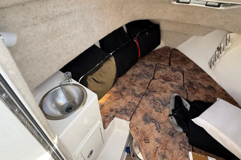 Slide: The Image of 2005 Mako 215 Walk Around cabin interior with sink and patterned cushions. - 15