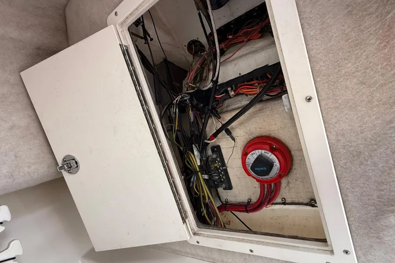Slide: The Image of Electrical compartment of a 2005 Mako 215 Walk Around boat, showing wiring and a Perko switch. - 17