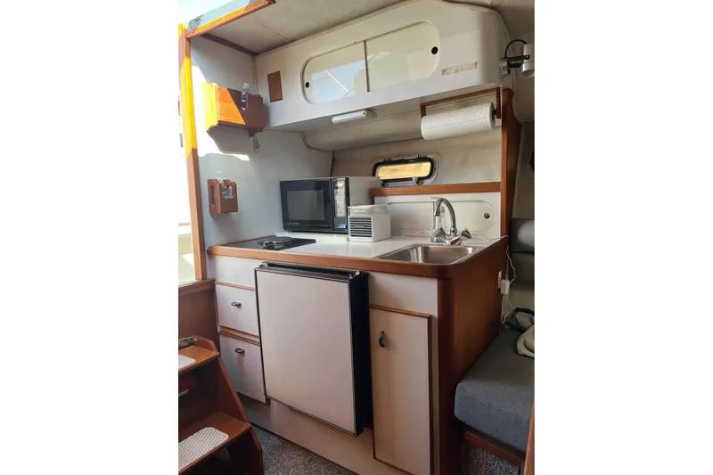 Slide: The Image of Interior of 1992 Tiara Yachts 2700 Open, featuring compact kitchen with sink, microwave, and storage. - 11