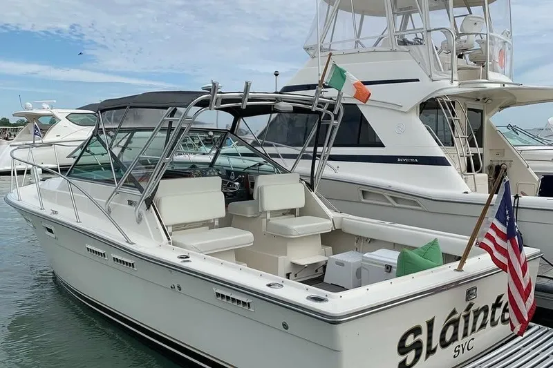 Slide: The Image of 1992 Tiara Yachts 2700 Open docked, featuring flags and spacious seating. - 9