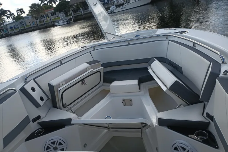 Slide: The Image of 2020 Blackfin 272 CC boat interior with cushioned seating and storage, docked by the water. - 29