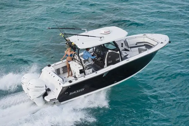 Slide: The Image of 2020 Blackfin 272 CC boat with dual Evinrude engines on a lift, cloudy sky background. - 4