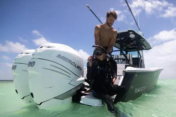 Slide: The Image of 2020 Blackfin 272 CC boat on a calm waterway, featuring dual outboard engines. - 8