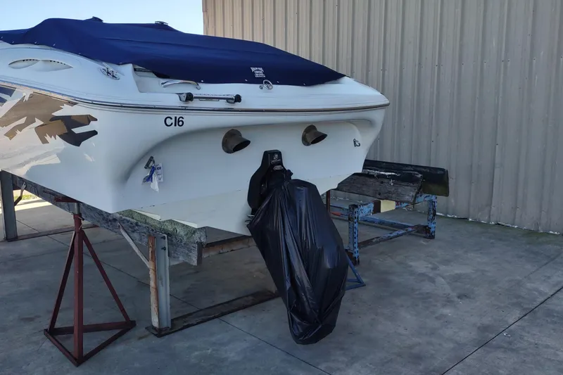Slide: The Image of 2004 Baja H2X boat on stands, covered, with outboard motor wrapped in black plastic. - 29