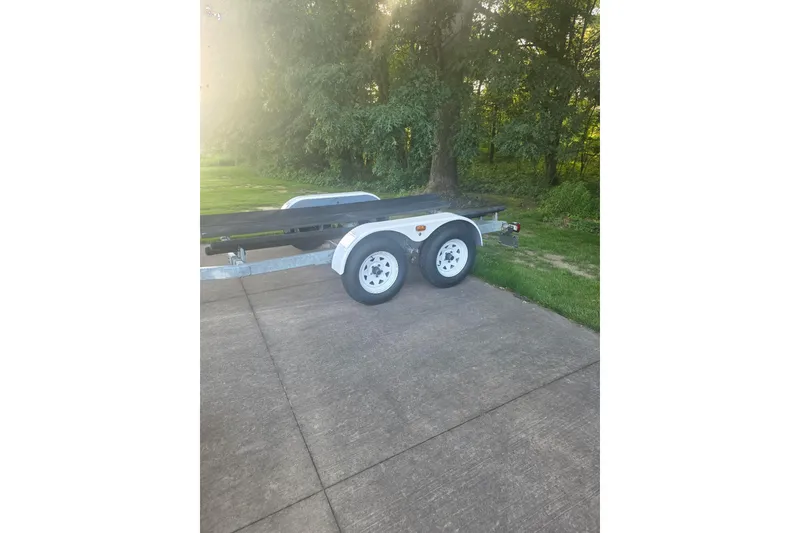 Slide: The Image of 2004 Baja H2X trailer parked on a concrete driveway near lush greenery. - 30