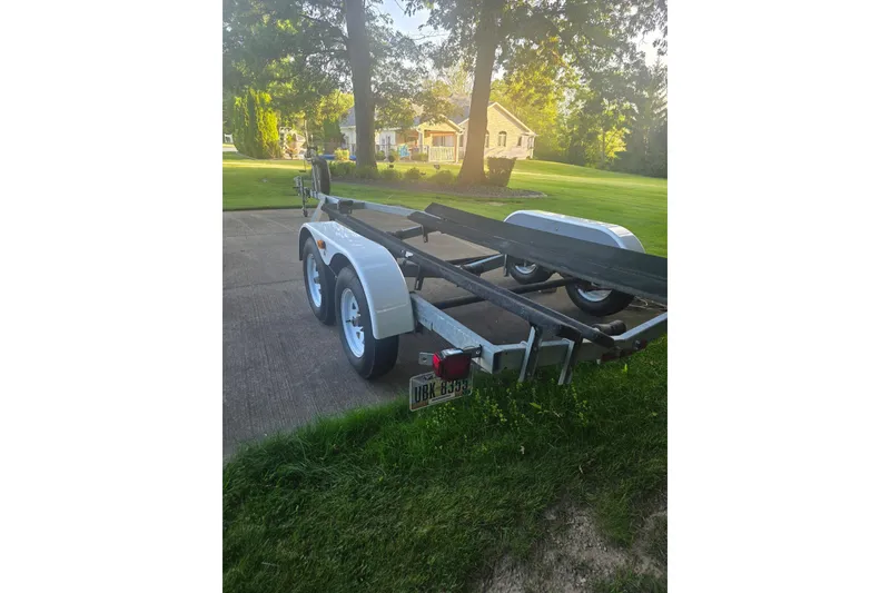 Slide: The Image of 2004 Baja H2X boat trailer parked on a driveway, surrounded by greenery. - 5