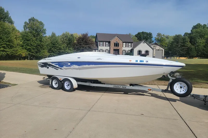 Slide: The Image of 2004 Baja H2X boat on trailer in suburban driveway, surrounded by trees and houses. - 8