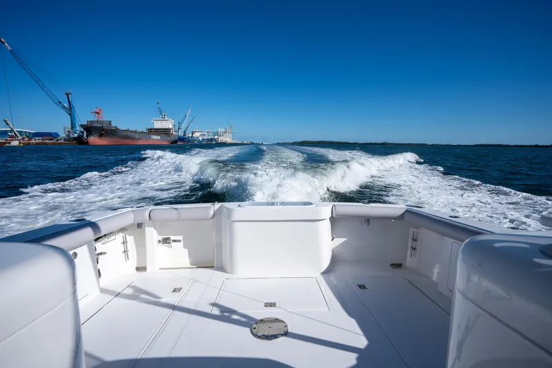 Slide: The Image of 2004 Cabo 35 Express boat cruising, leaving wake in harbor with ships and cranes. - 20