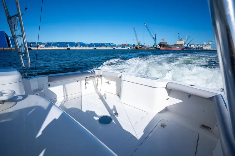 Slide: The Image of 2004 Cabo 35 Express boat cruising near industrial port with cranes and containers. - 21