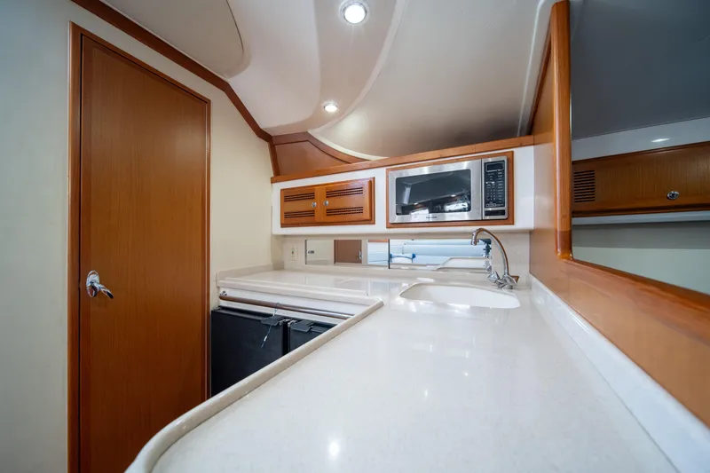 Slide: The Image of 2004 Cabo 35 Express yacht interior kitchen with microwave and sink. - 29