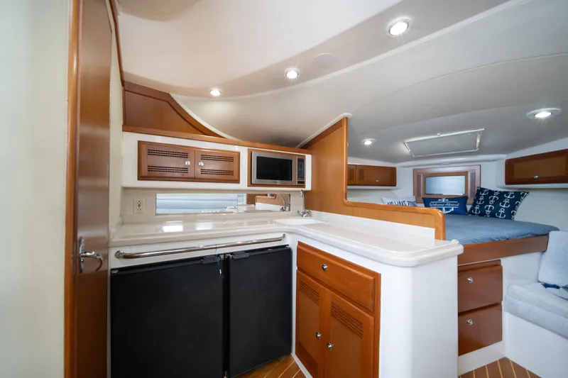 Slide: The Image of 2004 Cabo 35 Express yacht interior with kitchenette, microwave, and cozy sleeping area. - 30
