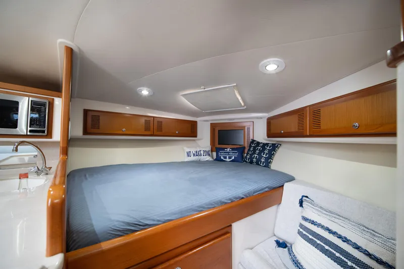 Slide: The Image of 2004 Cabo 35 Express cabin interior with bed, microwave, and cozy seating. - 31