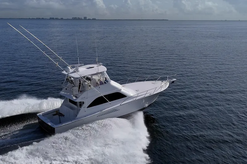 Slide: The Image of 2004 Viking 48 Convertible yacht cruising on open water, creating a dynamic wake. - 50