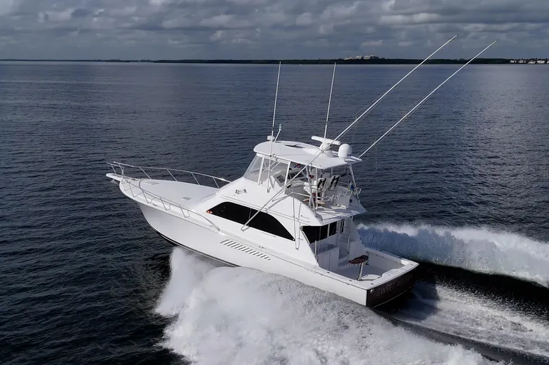 Slide: The Image of 2004 Viking 48 Convertible yacht cruising on open water under cloudy skies. - 52