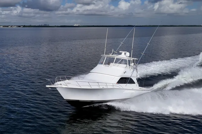 Slide: The Image of 2004 Viking 48 Convertible yacht cruising on open water under cloudy skies. - 53